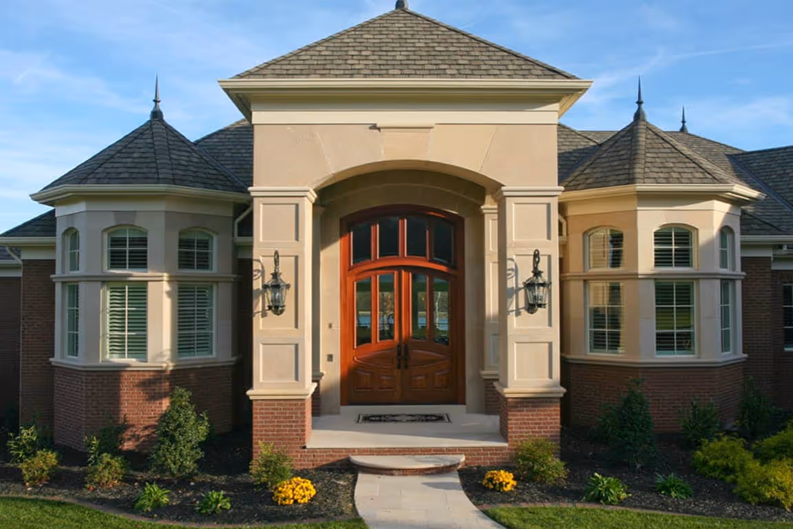 Entrance of a European Traditional style house with double wooden doors, symmetrical bay windows, and decorative exterior lighting.