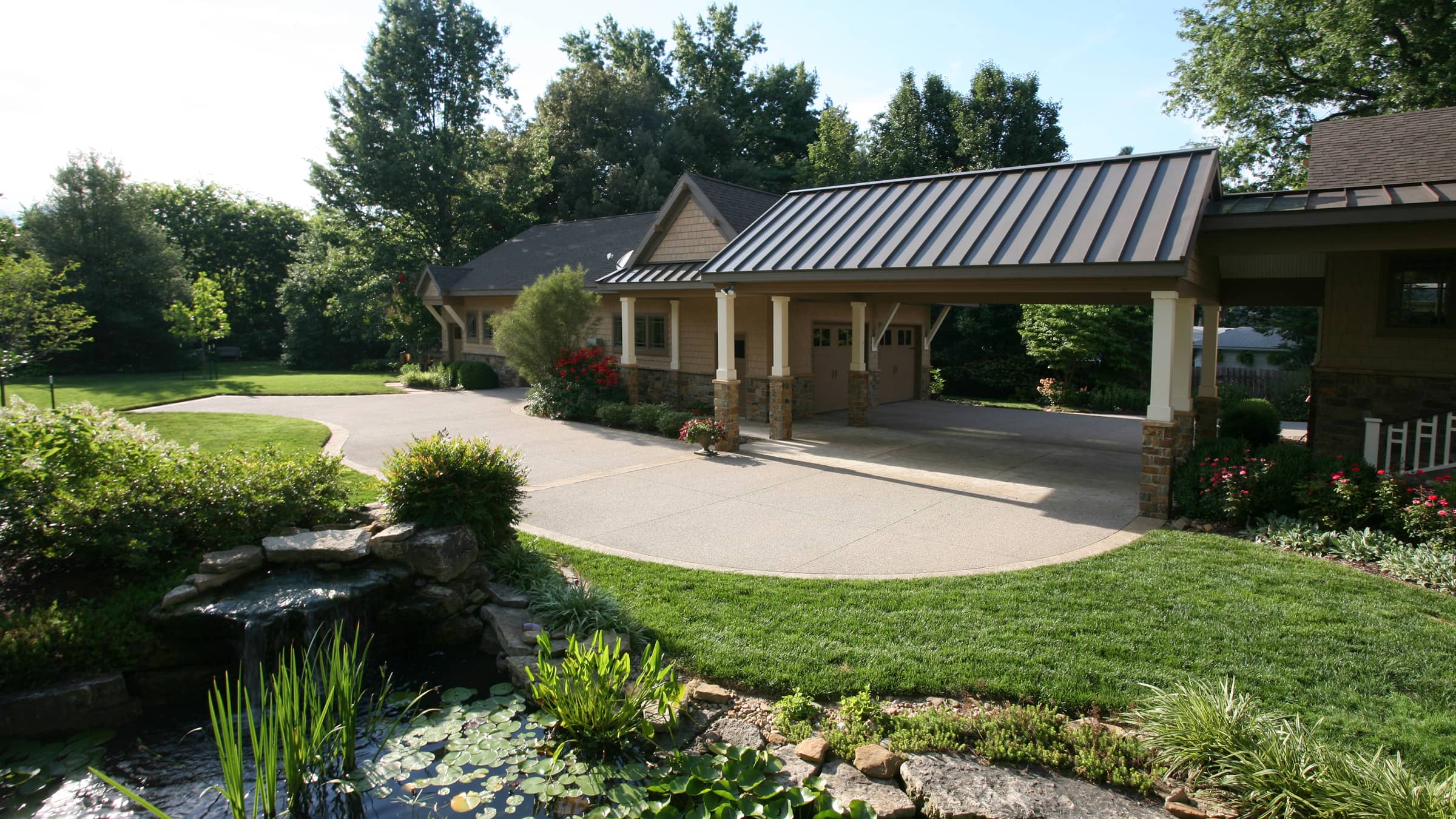 Prairie style house with a covered driveway and landscaped garden including a small pond with lily pads and a waterfall.