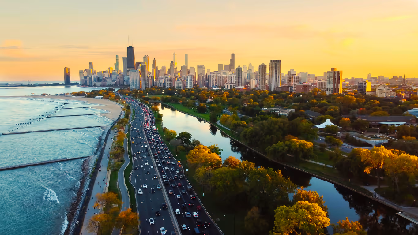 Chicago skyline at sunset with busy highway, autumn foliage, and Lake Michigan waterfront.