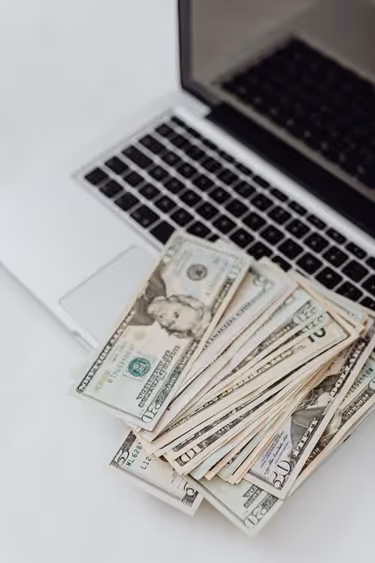 Pile of cash on top of an open laptop