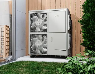 Outdoor HVAC unit with two large fans installed against a wooden fence, surrounded by grass and plants near a house wall with a glass door.