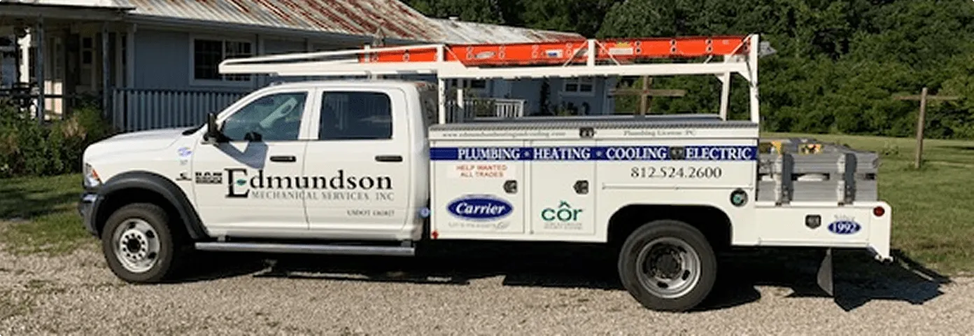 White Edmundson Mechanical Services work truck with ladder on top and business signage for plumbing, heating, cooling, and electric services.