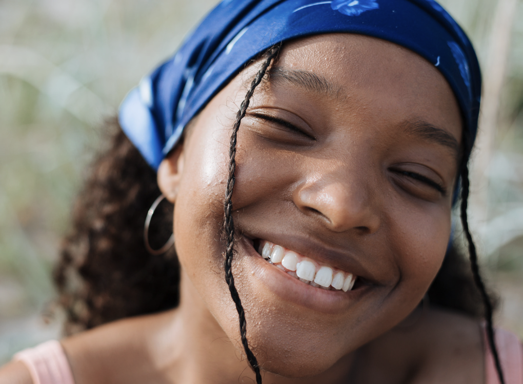 Close-up of the left side of a smiling woman's face with smooth skin and dark hair.