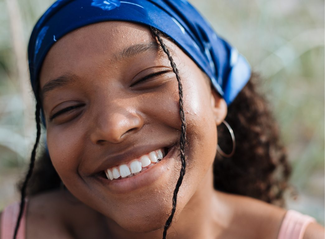 Close-up of the left side of a smiling woman's face with smooth skin and dark hair.