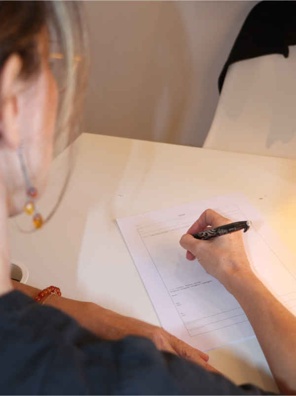 Pamela de dos en train de compléter une fiche bilan posée sur un bureau