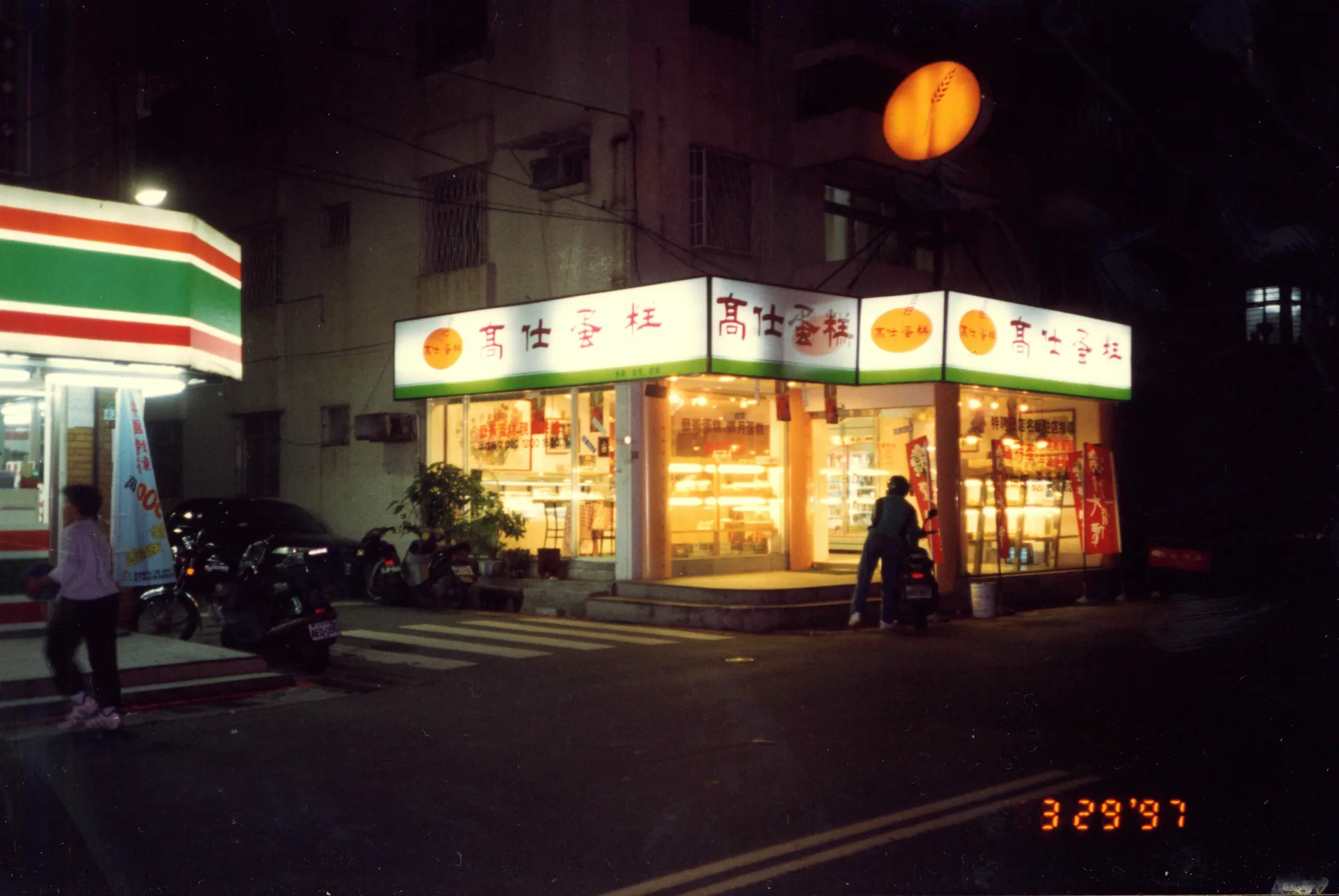 1997 年夜晚的高仕蛋糕老店門口，招牌燈箱亮起