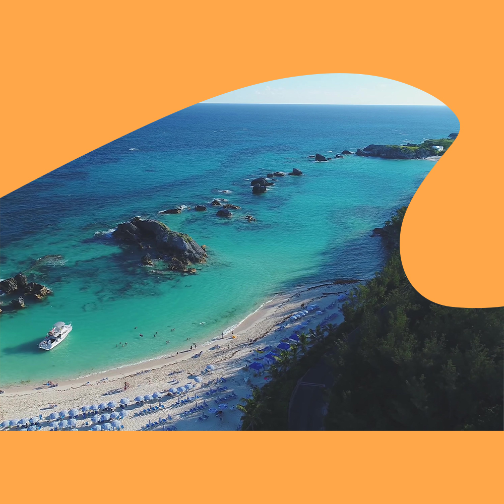 An aerial view of the beachfront along the Fairmont Southampton, with rows of beach chairs and umbrellas peppering the beach.