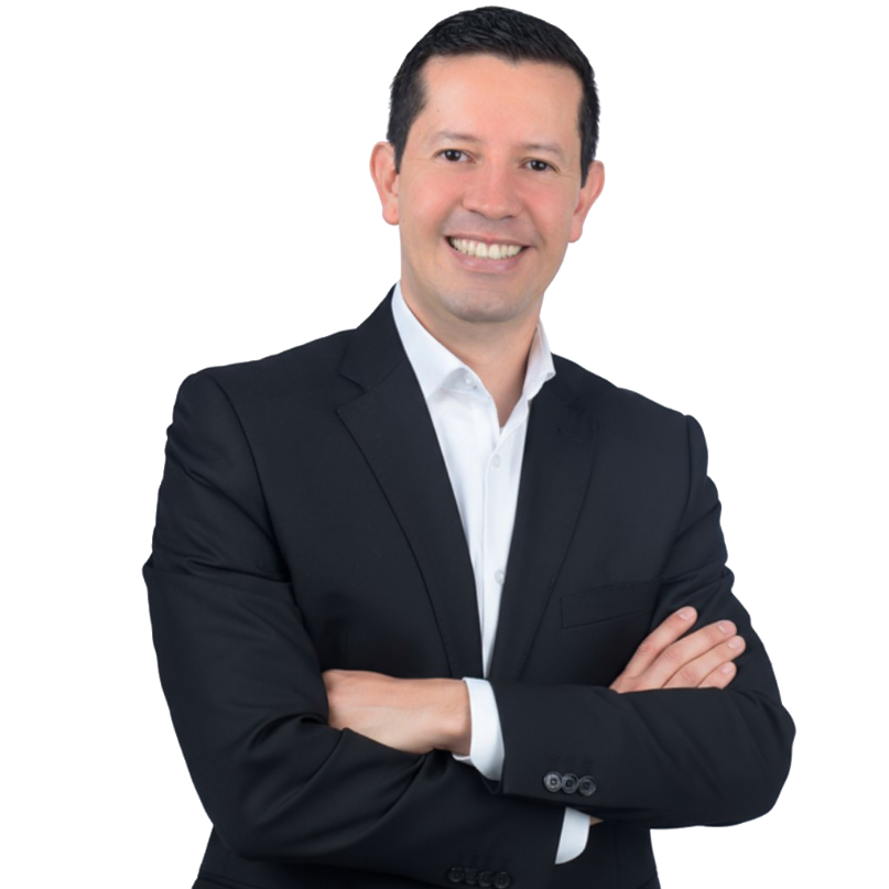 Hombre sonriente con traje oscuro y camisa blanca con los brazos cruzados.