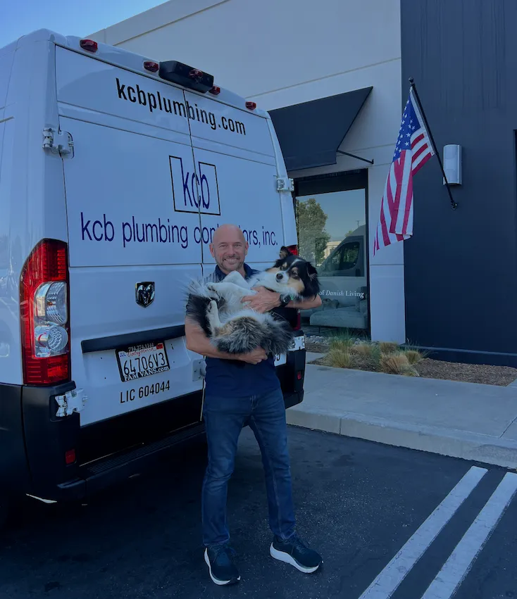Keevin Blue, owner of KCB Plumbing, with service dog next to company van in Orange County