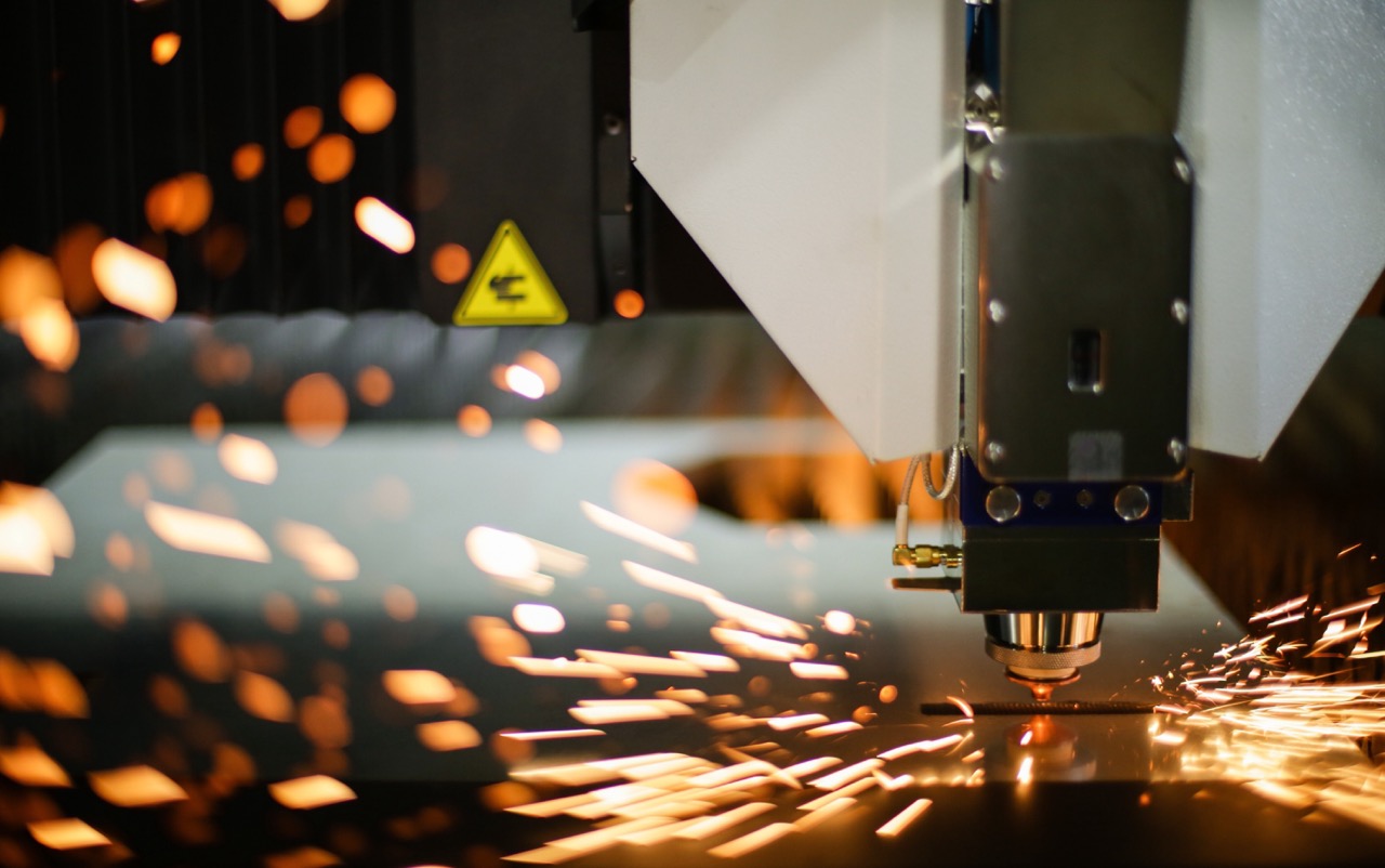 A laser manufacturing tool creates sparks on a metal sheet