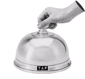 A black and white image of a hand holding a cloche. The cloche has a label that reads 'tap' 