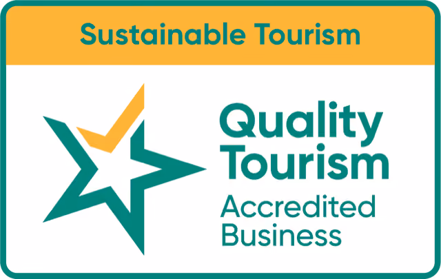 Badge with text 'Sustainable Tourism' at the top, and below a green and yellow star symbol with the words 'Quality Tourism Accredited Business.'