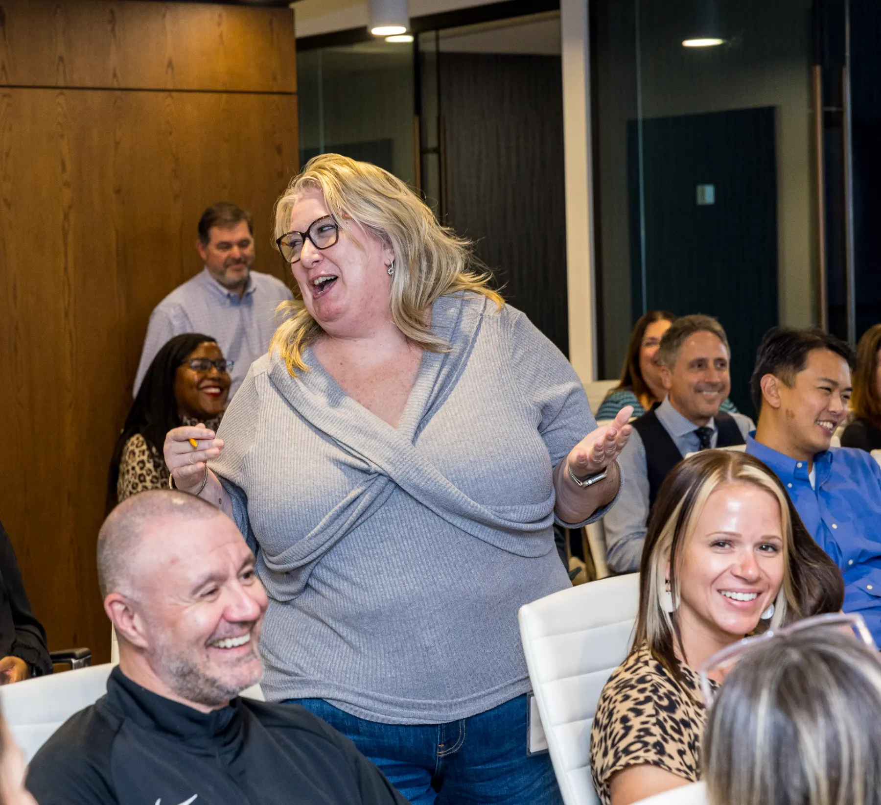 An attendee stands among seated colleagues during an interactive moment of the magic show