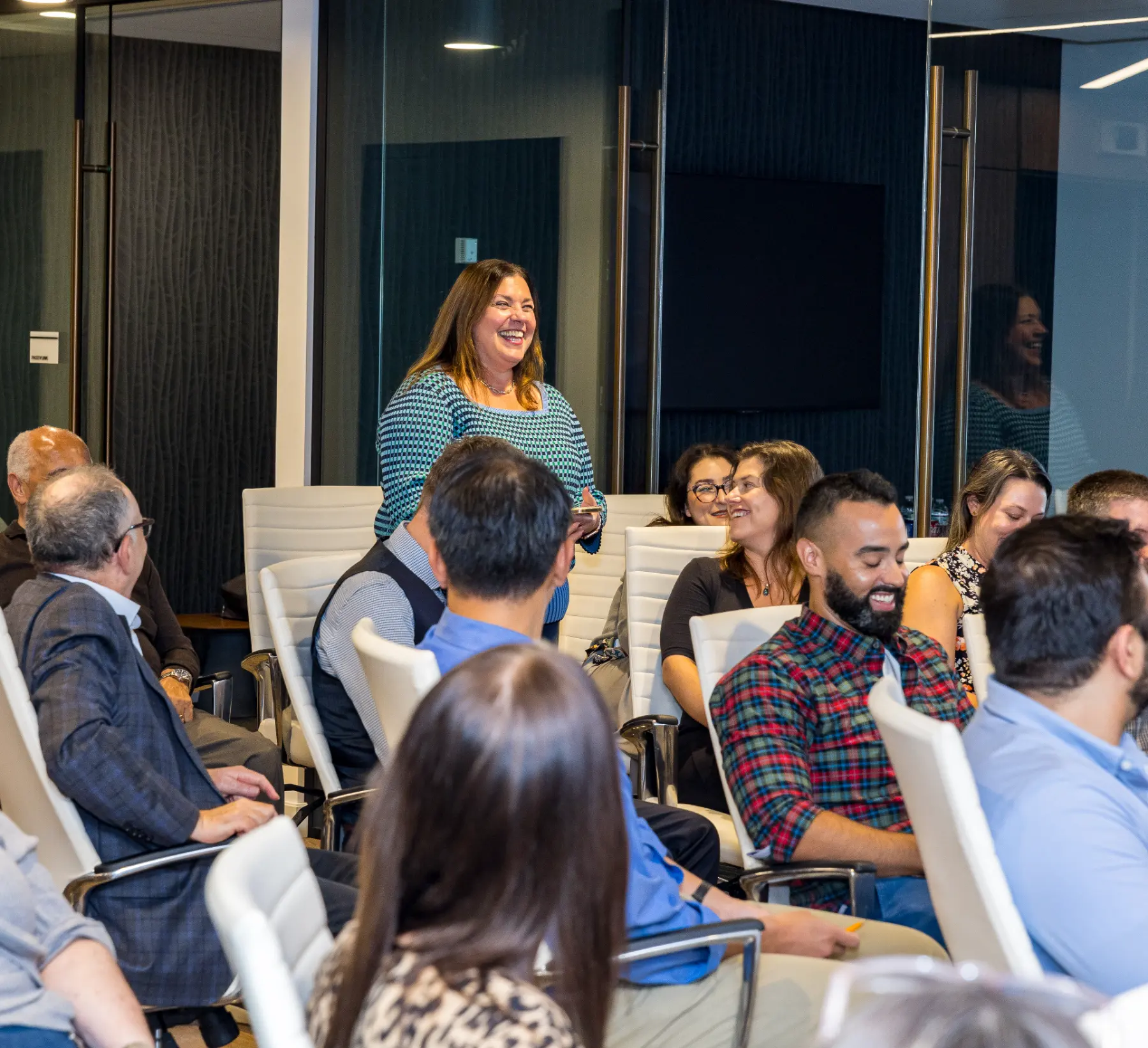 An attendee laughs while standing among seated colleagues during a playful exchange with Jesse