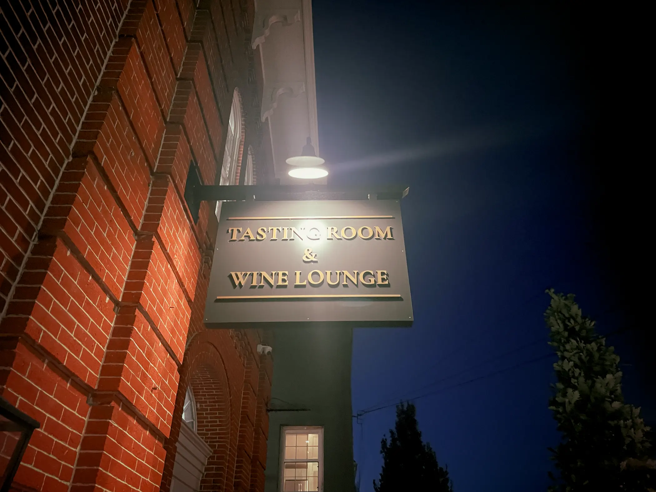 Illuminated "Tasting Room & Wine Lounge" sign mounted on the brick exterior of Turks Head Wines in downtown West Chester, PA.