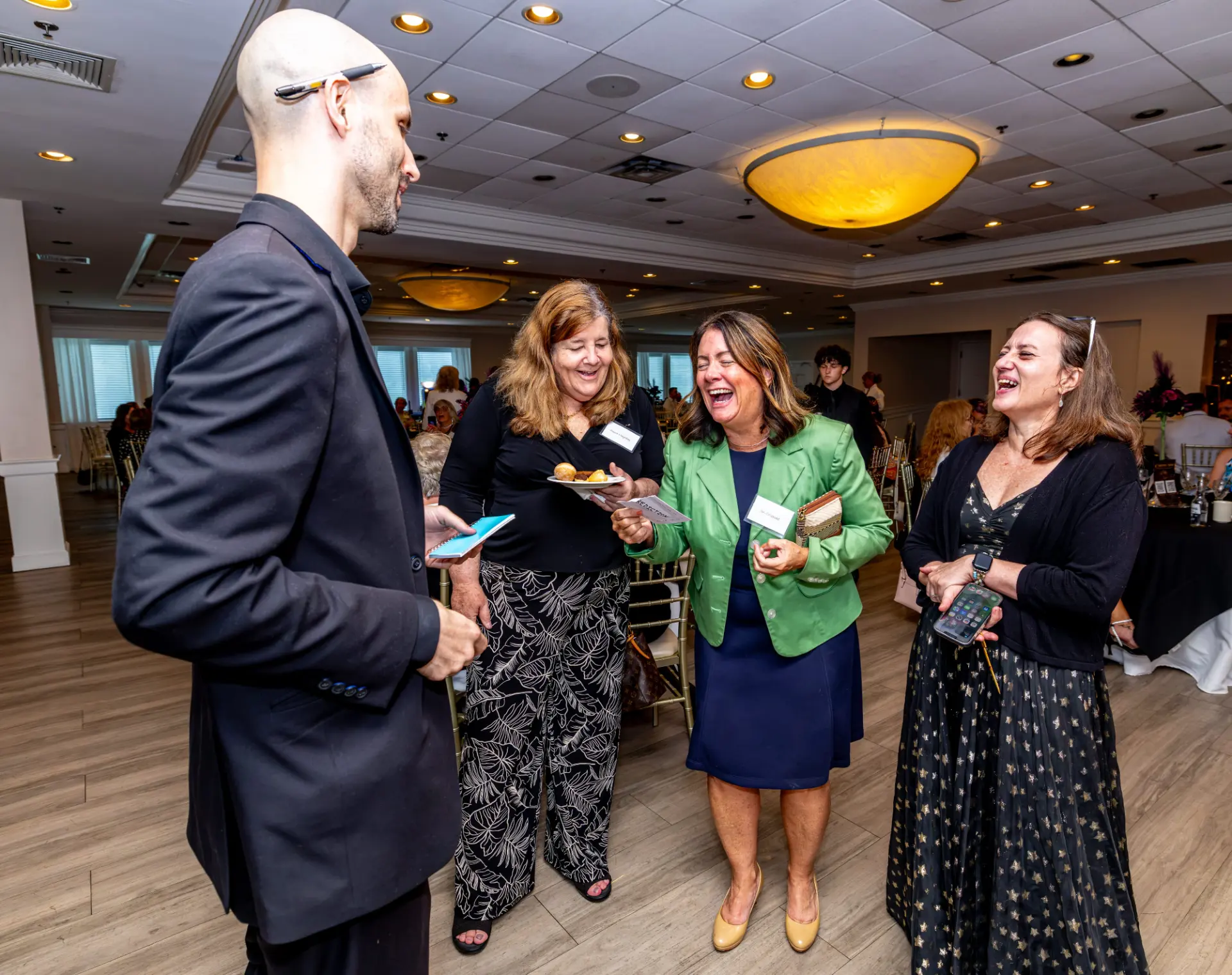 Three guests laughing during a roaming performance by magician and mentalist Jesse Dameron
