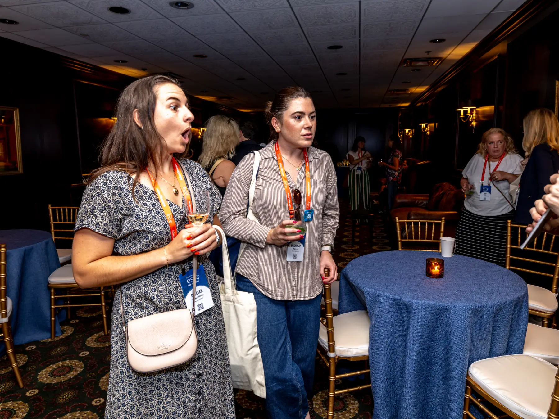 Two ESTO attendees react to a performance by magician and mentalist Jesse Dameron in the dark, wood-paneled Wanamaker Lounge