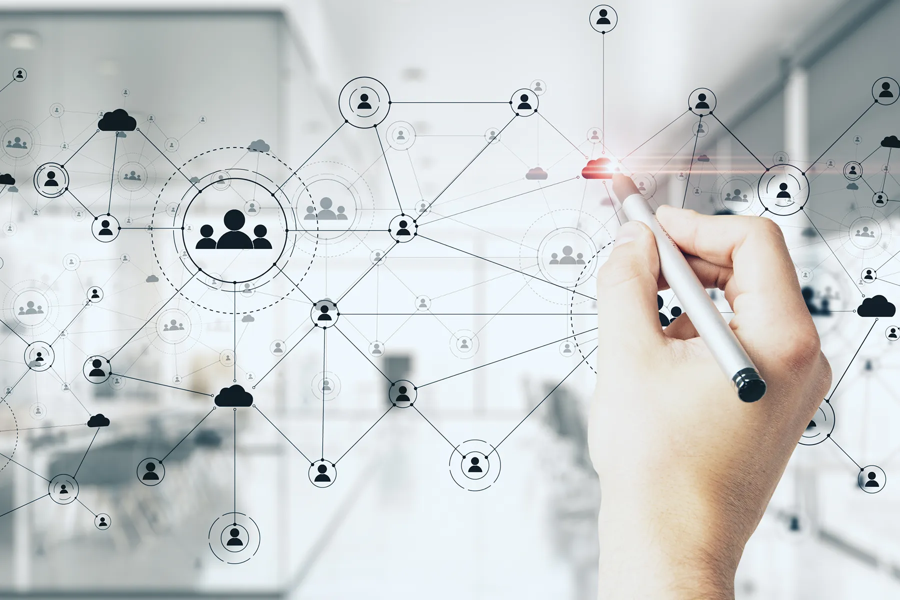 Hand holding a pen interacting with a digital network of connected user icons and cloud symbols representing data interoperability.