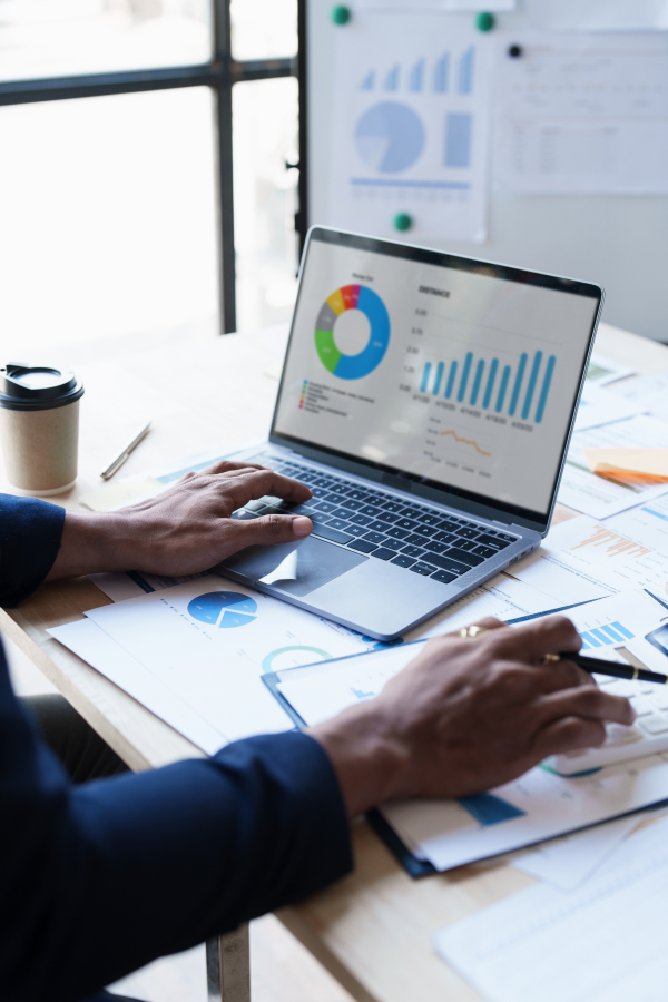 Hands of business people pointing and discussing charts and graphs on printed reports at a desk.