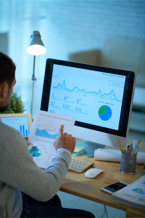 Hands of business people pointing and discussing charts and graphs on printed reports at a desk.