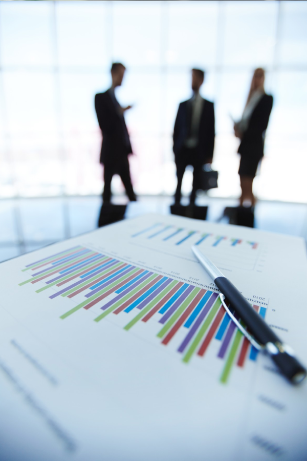 Hands of business people pointing and discussing charts and graphs on printed reports at a desk.