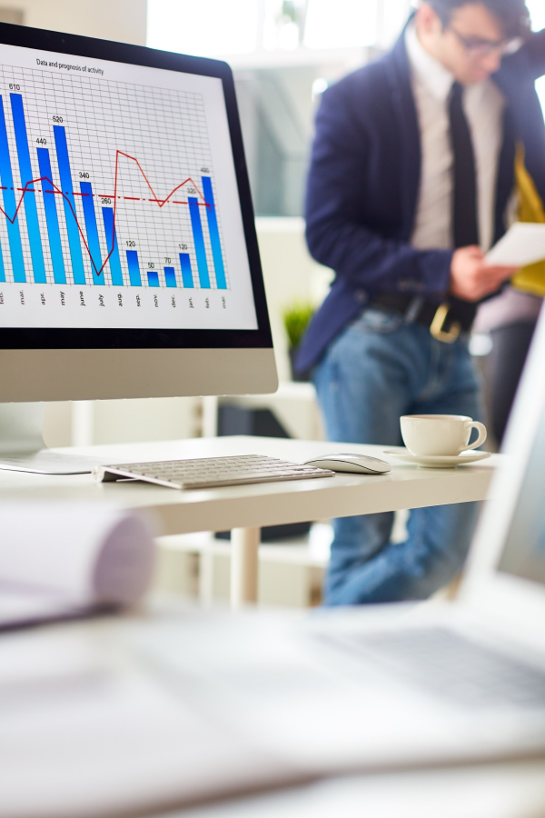 Hands of business people pointing and discussing charts and graphs on printed reports at a desk.