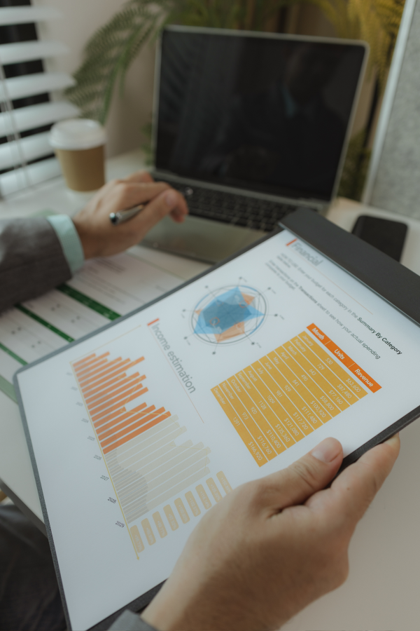 Hands of business people pointing and discussing charts and graphs on printed reports at a desk.
