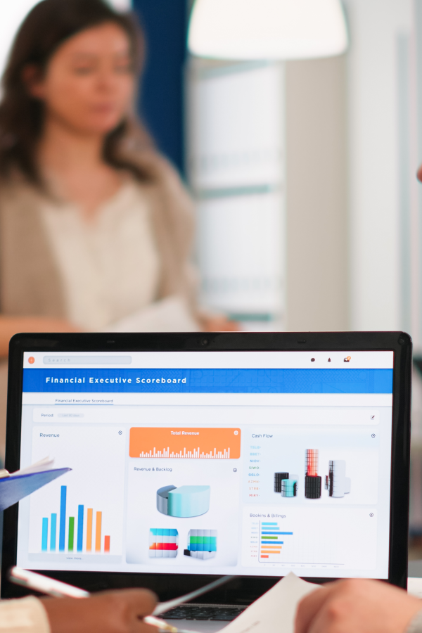 Hands of business people pointing and discussing charts and graphs on printed reports at a desk.
