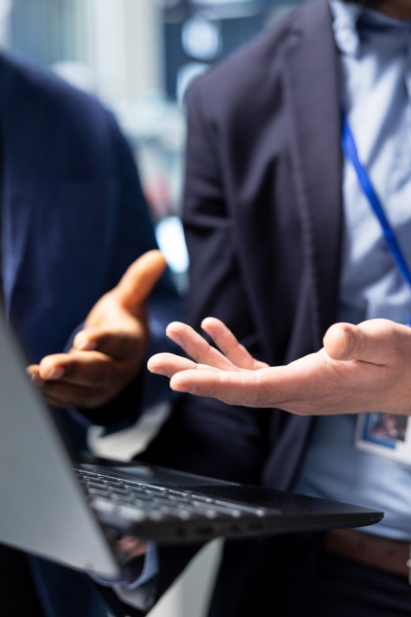 Hands of business people pointing and discussing charts and graphs on printed reports at a desk.