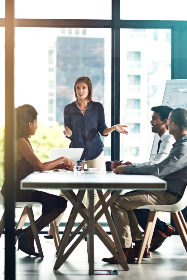 Hands of business people pointing and discussing charts and graphs on printed reports at a desk.