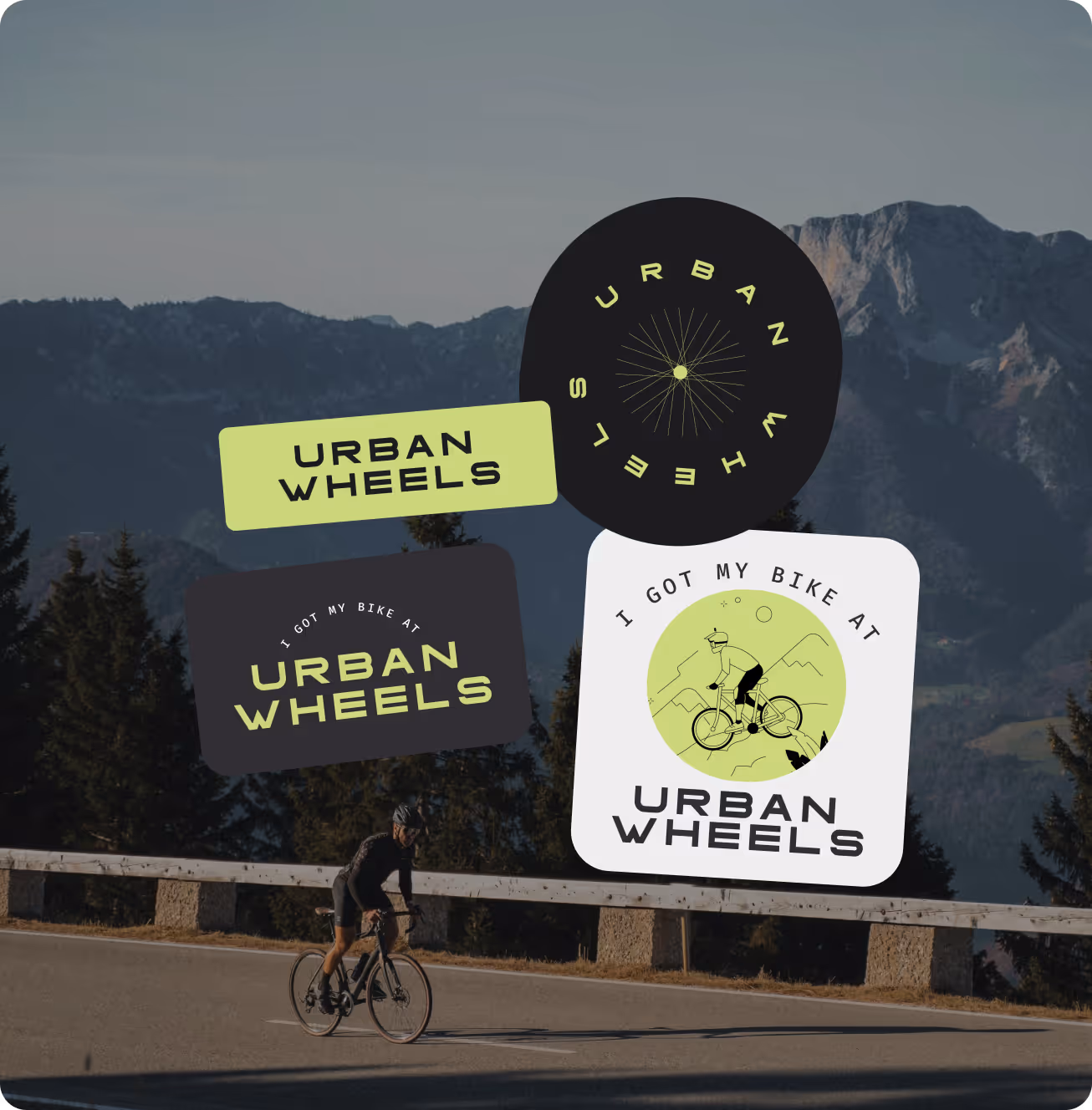 Cyclist riding on a paved mountain road with four 'Urban Wheels' stickers overlaid against a backdrop of trees and distant mountains.
