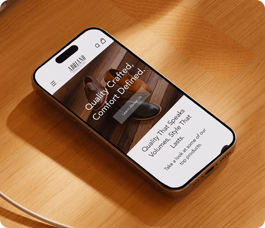 Smartphone on wooden surface displaying a website with shoes and text about quality crafted comfort.