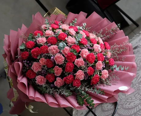 A bouquet of red and pink carnations on a table.