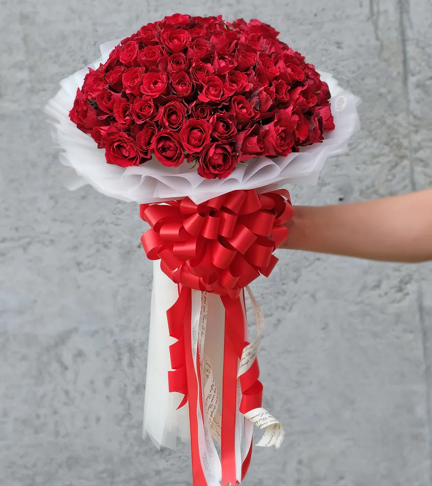 A person holding a bouquet of red roses.
