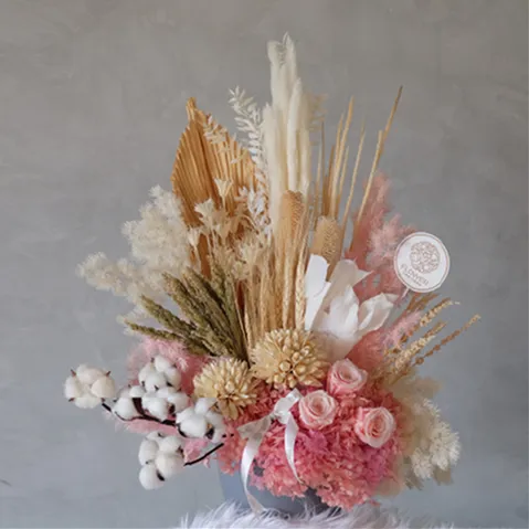 A vase filled with flowers and feathers on top of a table.
