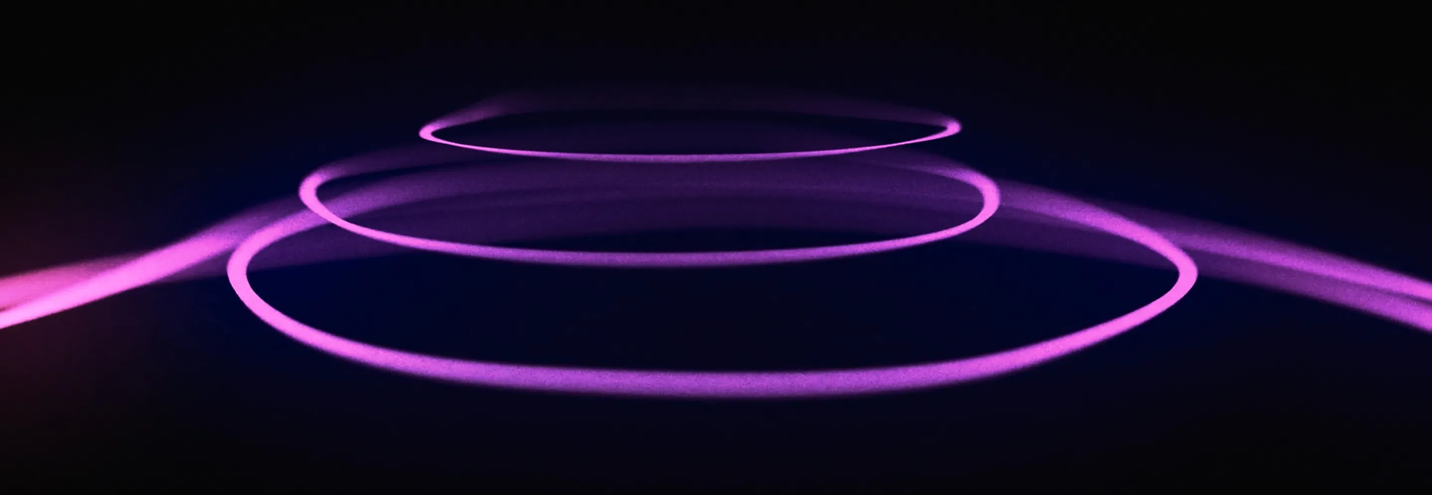 Three glowing purple rings of light floating horizontally in a dark space, creating a futuristic and abstract visual effect.