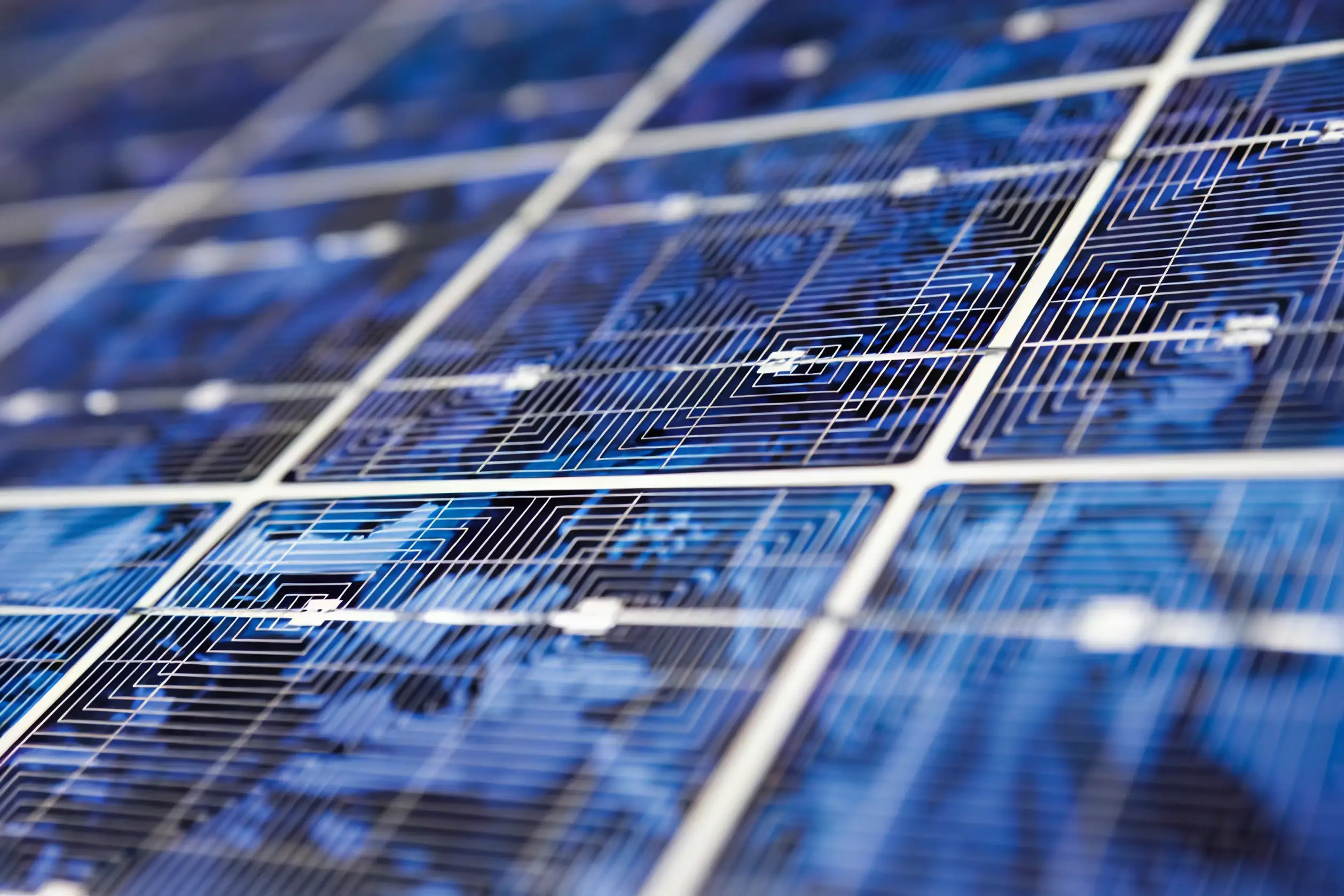 Close-up of blue photovoltaic solar cells showing fine conductive grid patterns and geometric textures used in renewable energy technology.