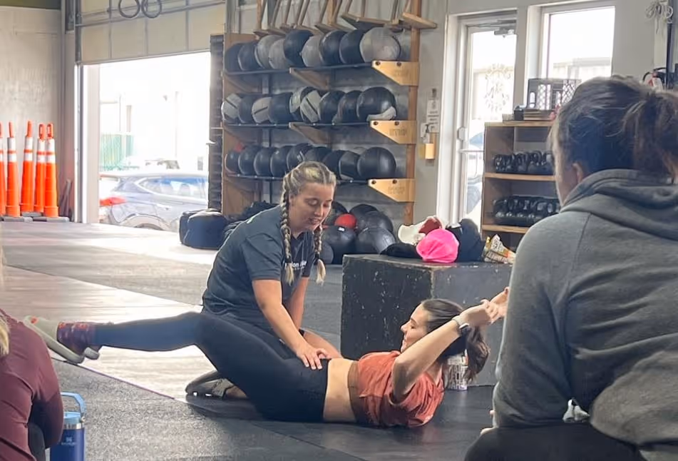 Physical therapist at Elevation Athletics in Fort Worth guiding a woman through pelvic floor core exercise in the gym