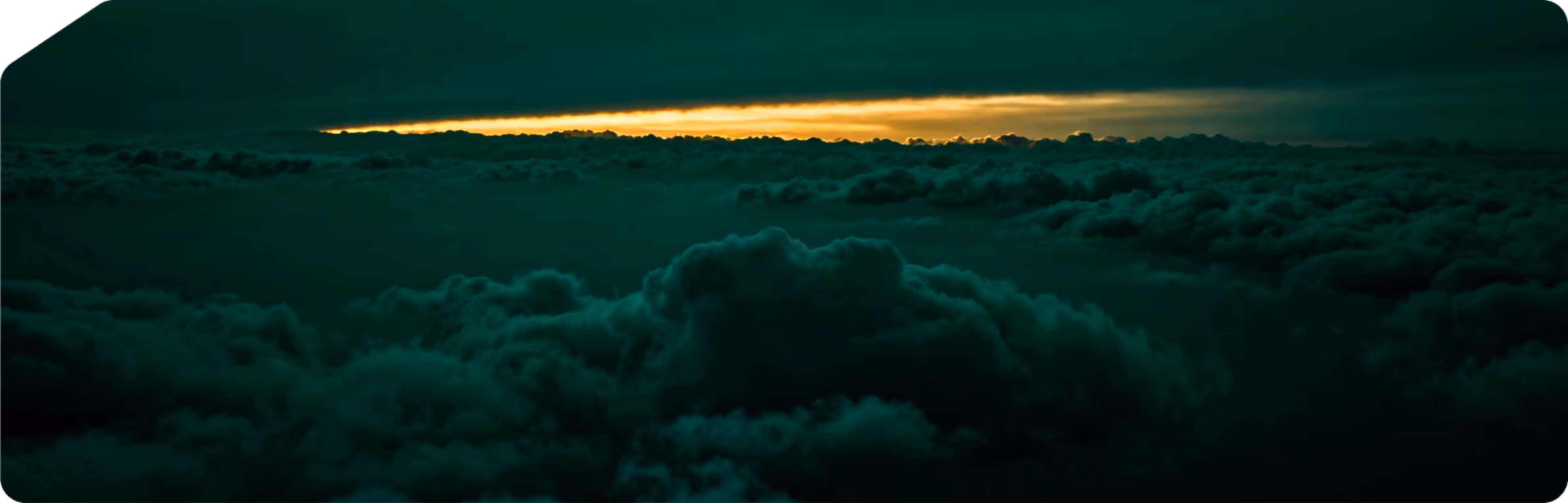 Dunkle Wolken mit einem schmalen Streifen goldenem Sonnenlicht am Horizont.