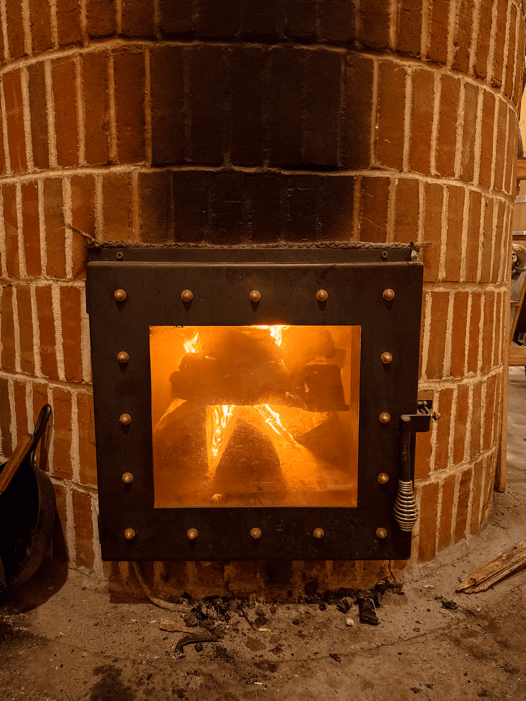 Blazing fire inside a brick fireplace with metal door and rivets