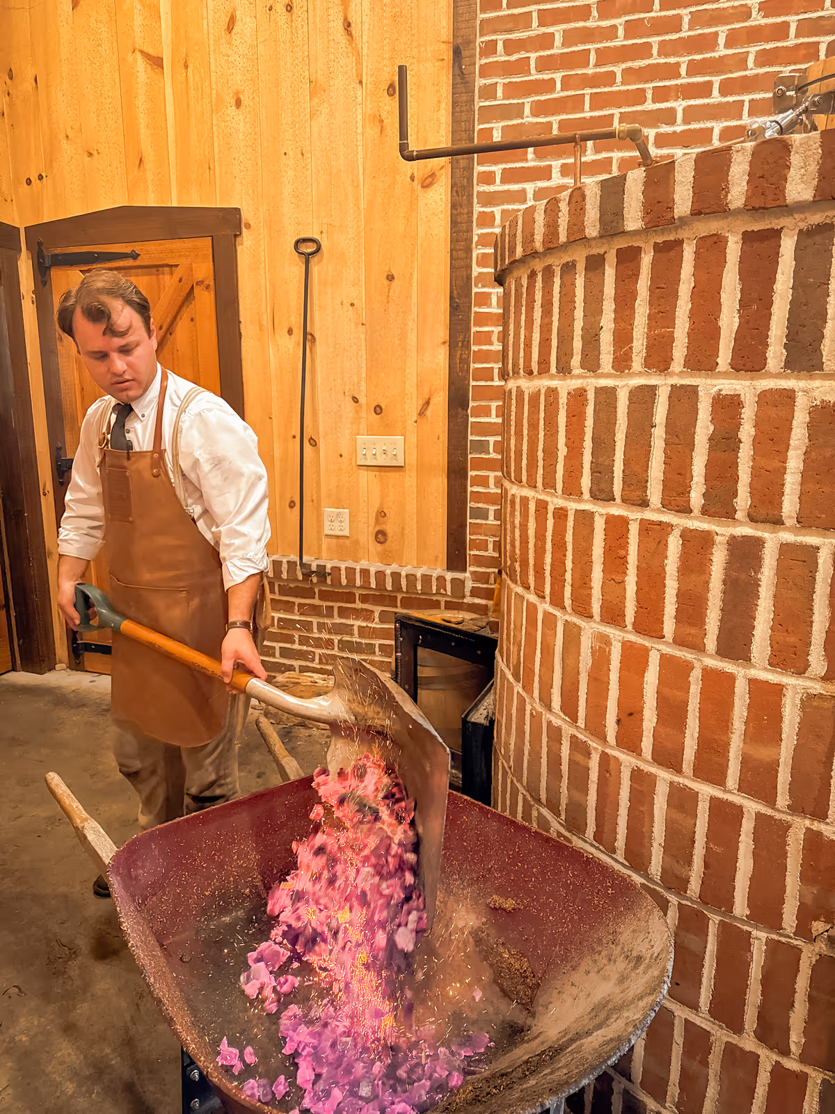 Worker in apron shovels bright pink flower petals into large metal container