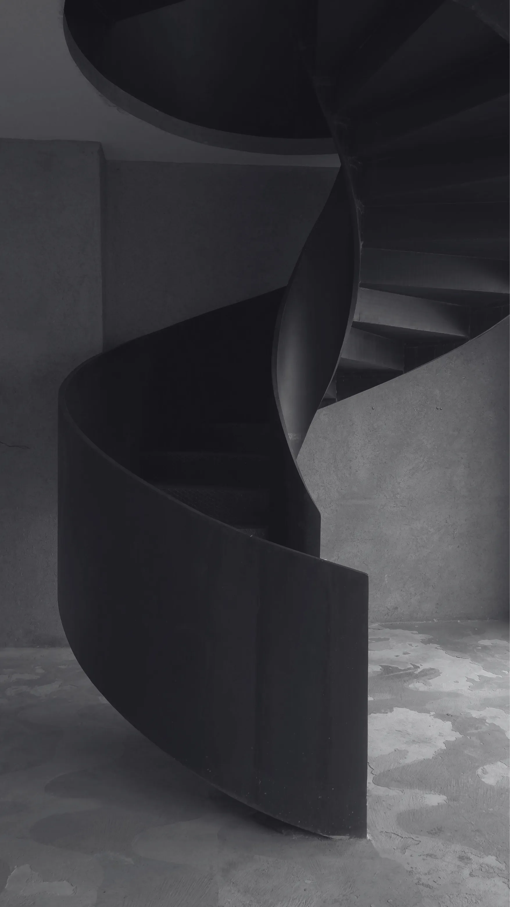 Blackened steel spiral staircase rising through the Rigotang gallery space in Marrakech