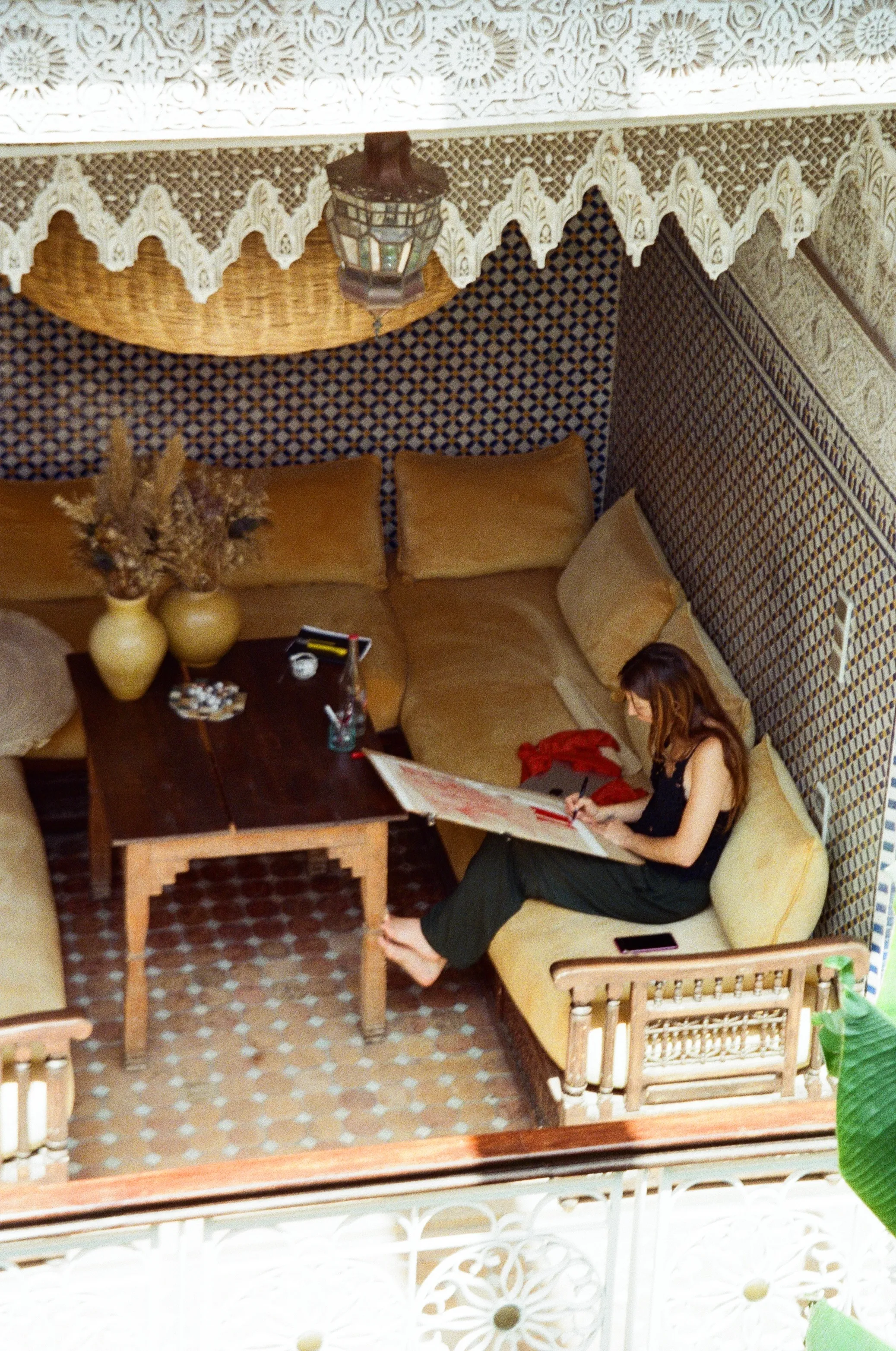 An artist drawing in a tiled alcove of Riad Jardin Secret, Marrakech, during a residency