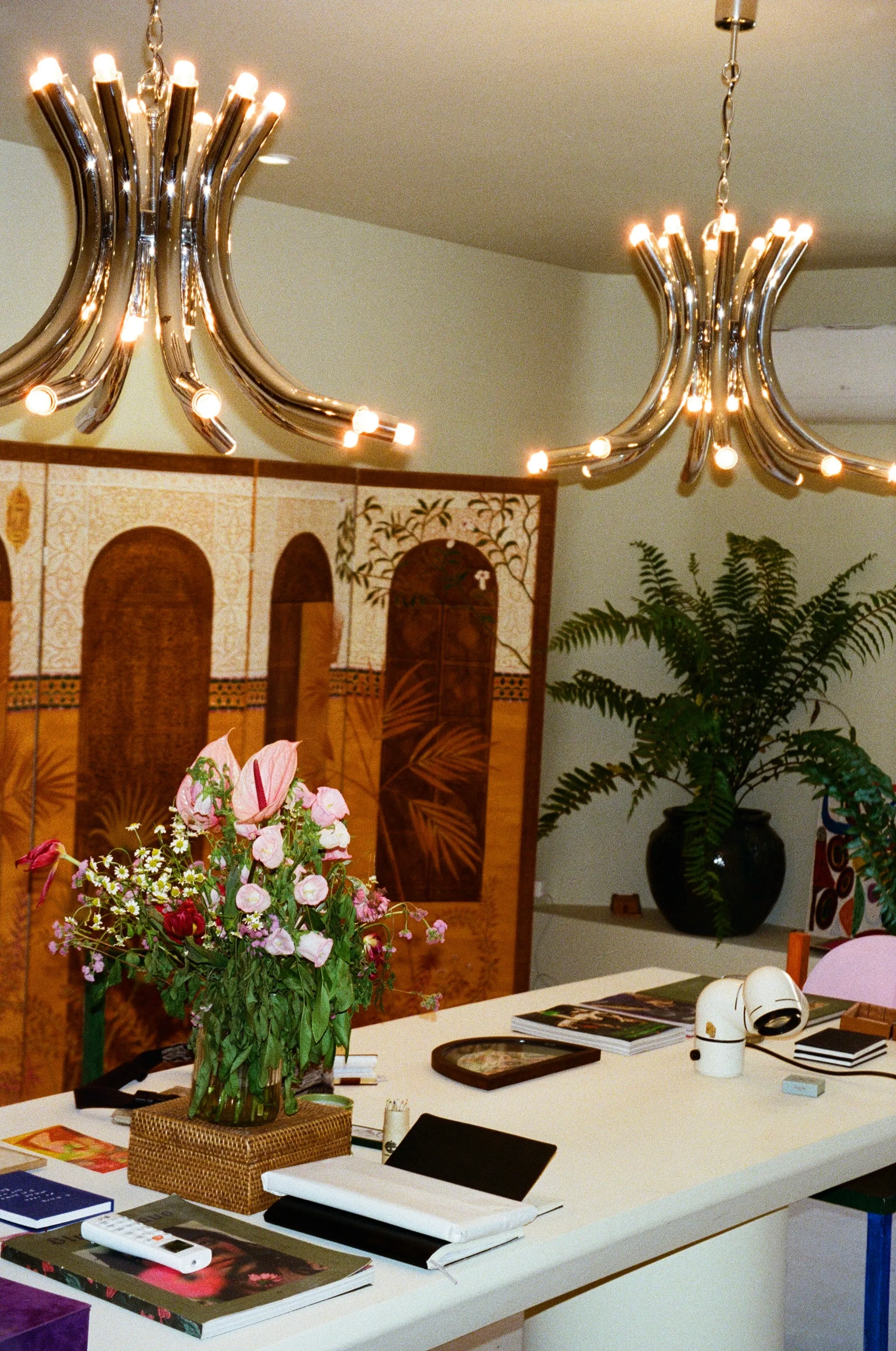 The Rigotang gallery reception: chrome chandeliers, flowers and art books on a white table