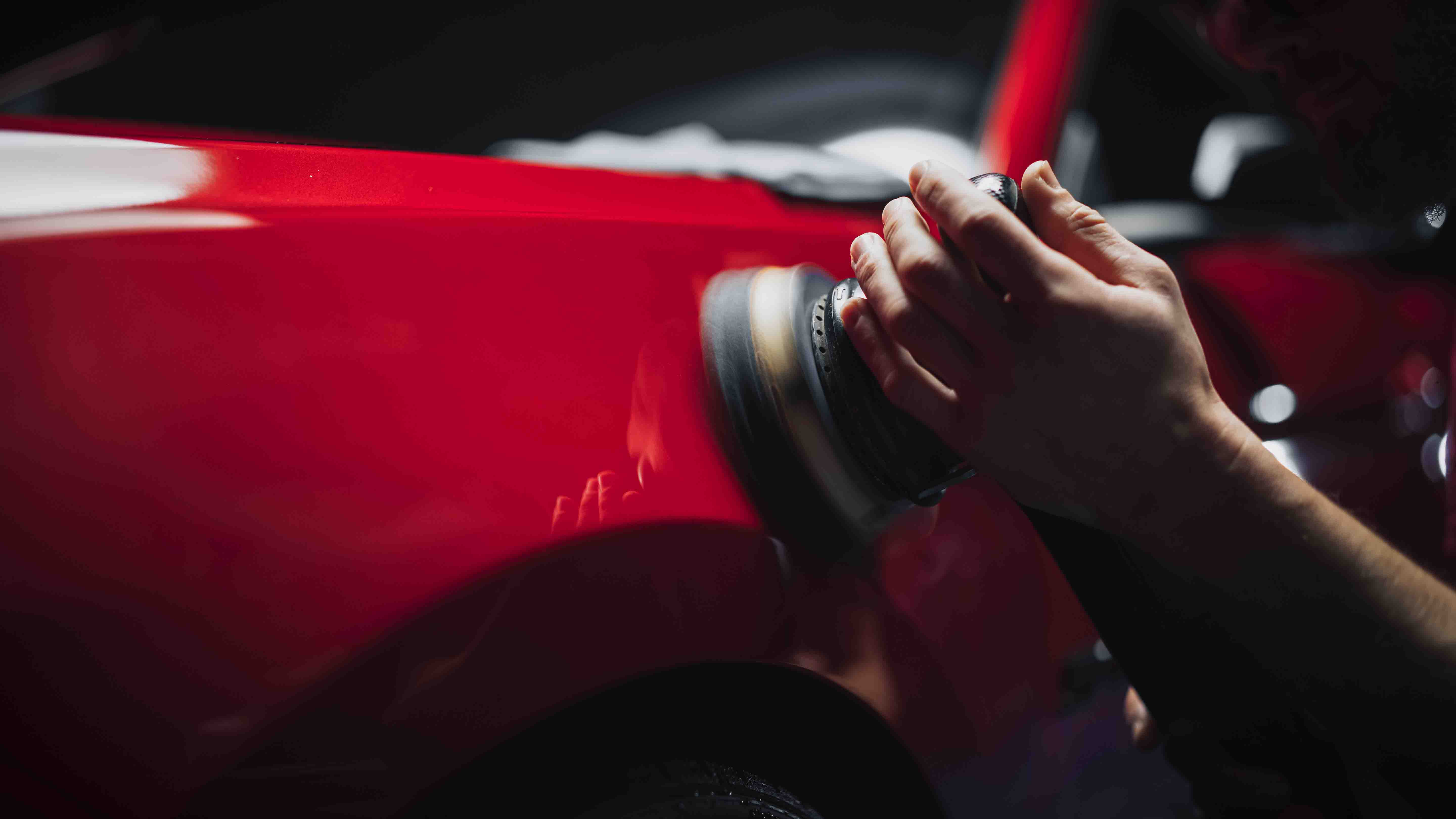 A hand holding a small vial over a robotic apparatus inside a laboratory setup, with visible mechanical components in the background.