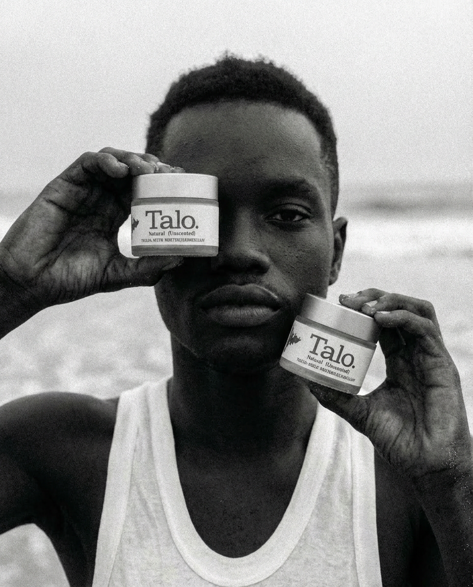 Black and white photo of a man wearing a white tank top holding two jars of Talo Natural (Unscented) cream near his face.