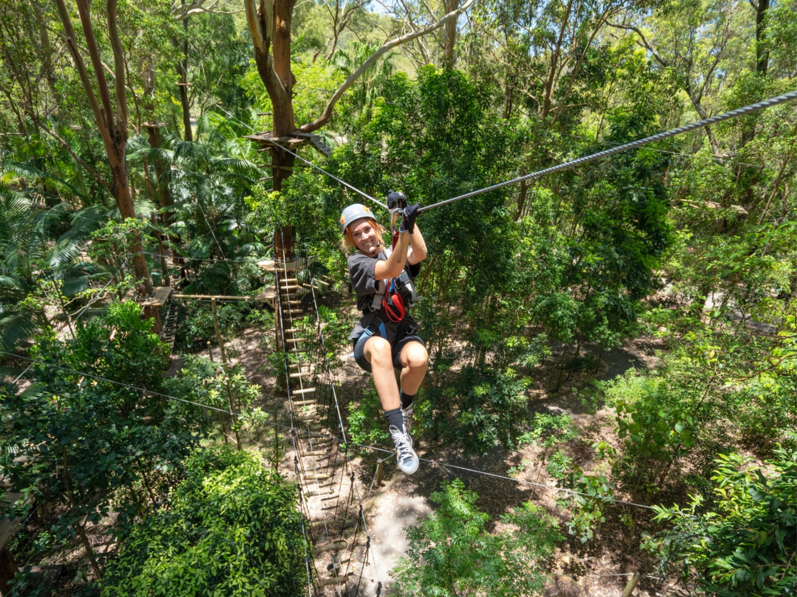 A woman smiling while ziplining on our TreeTop High Ropes Park at Currumbin