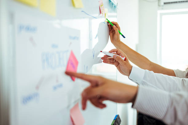 Group of coworkers standing around a table and joining their fists together in a team-building gesture, showing unity and collaboration.
