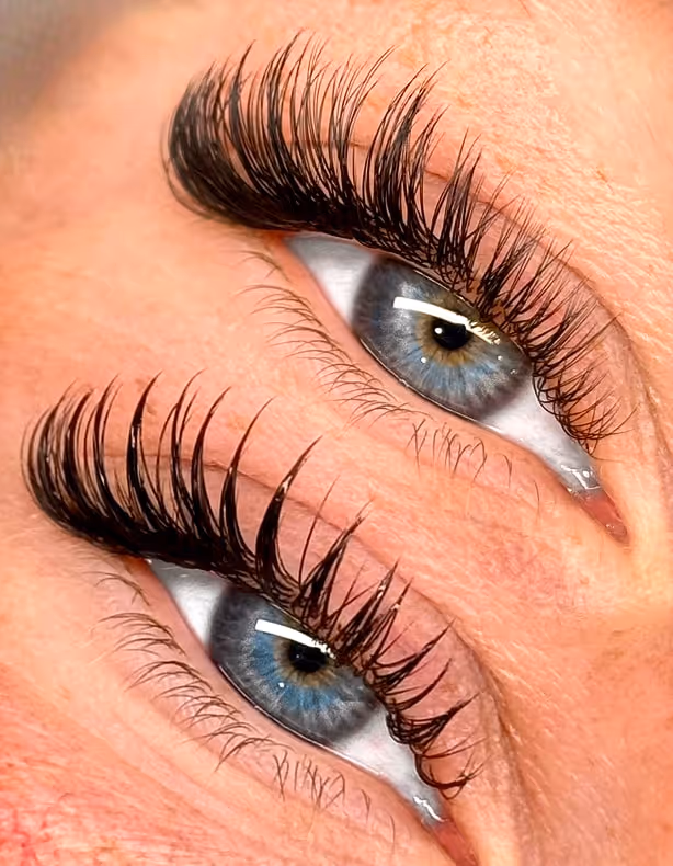 Close-up of two blue eyes with long, thick eyelashes and natural skin texture.