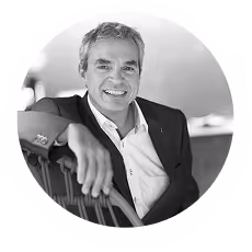 Lächelnder älterer Mann in einem Anzug, der sich entspannt auf einer Bank zurücklehnt.